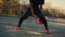 Young man dribbling a basketball on an outdoor court on a sunny day