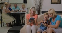 Grandmothers and grandchild with electronics at home