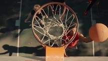 Young men playing basketball on an outdoor court on a sunny day