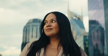 Young woman admiring downtown city buildings and scenery during sunset