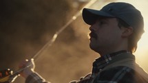 Young fly fisherman casting on a foggy river at sunrise