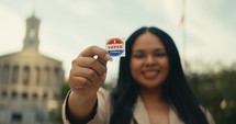 Young woman smiling with an ‘I Voted’ stickers and pin 