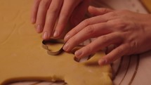 Young woman Cutting and examining heart shaped valentines day cookies