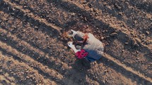 Aerial view of huge field. Experienced woman farmer manually checks soil ground condition of land before growing seeds or plant. Agricultural production. Cultivation big scale natural healthy food.