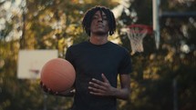 Portrait of a smiling young man playing basketball on a sunny day