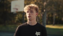 Portrait of a smiling young man playing basketball on a sunny day