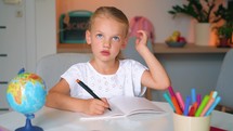 Portrait of exhausted sad primary child school girl studying feeling headache writing difficult assignment at home. Tired pupil schoolgirl writing hometask in notebook. The concept of online and home