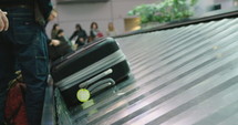 Passengers collecting luggage from a conveyor belt at the airport