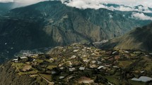Aerial View Of Town With Lush Green Fields And Tungurahua Volcano In Background In Ecuador - drone shot	