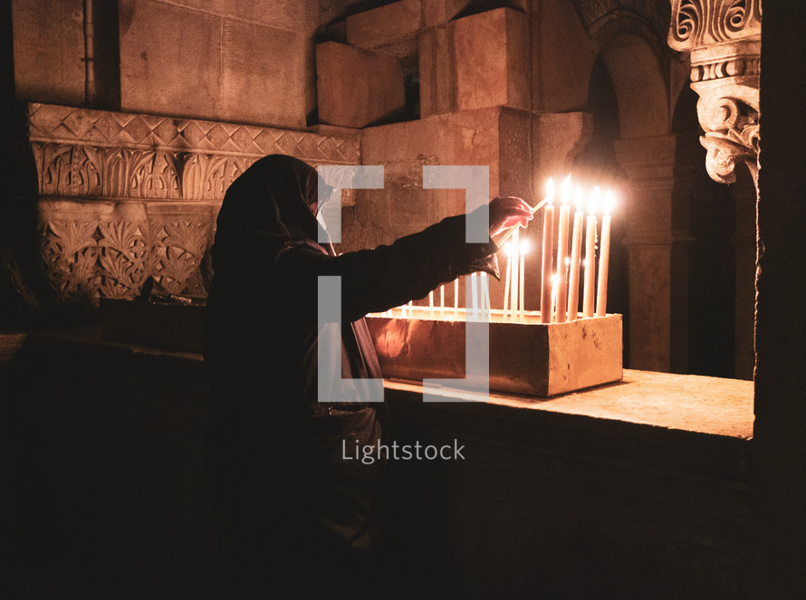 woman lighting prayer candles 