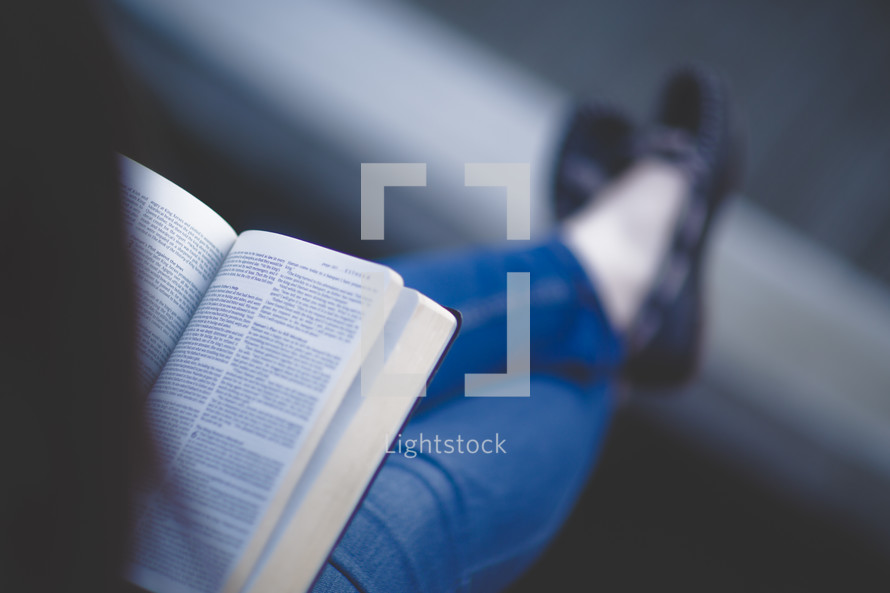 a woman sitting reading a Bible in her lap 