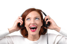A woman listening to headphones with an excited look on her face.