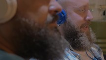 Close up view of two bearded men listening musics 