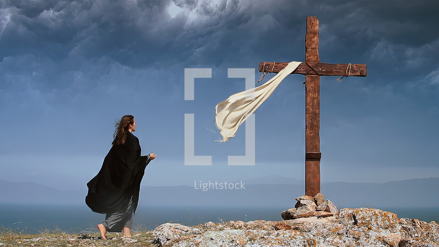 A woman in a black cape approaches the Holy Cross on a stormy day.
