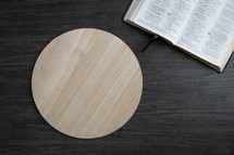 Open bible and copy space on round light wood tray on a dark background