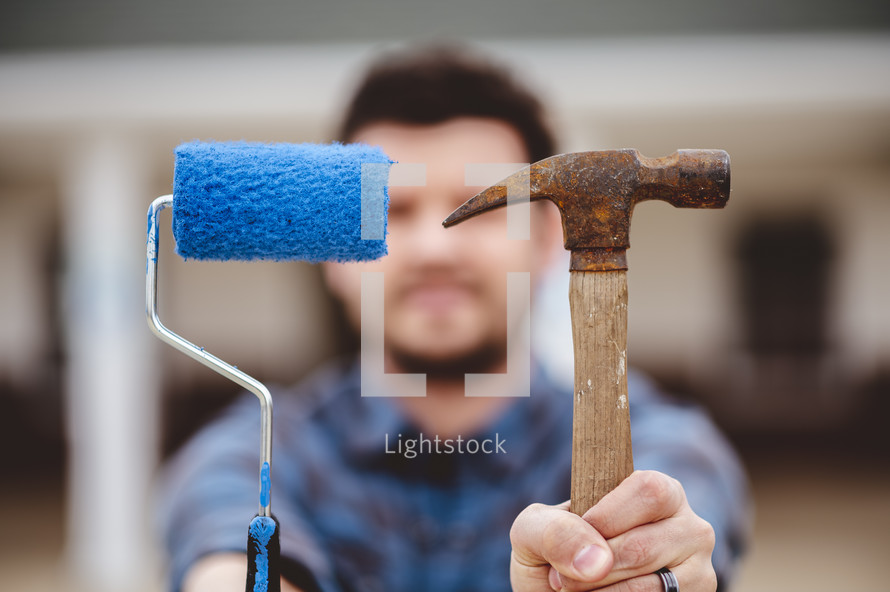 a man holding a paint roller and hammer 