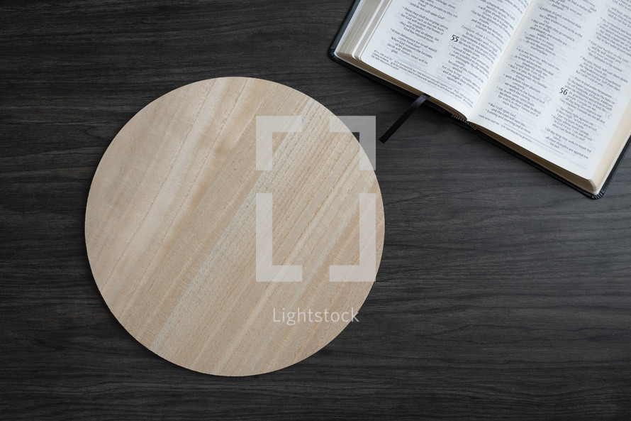 Open bible and copy space on round light wood tray on a dark background