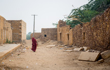 a woman walking on a dirt road in India 