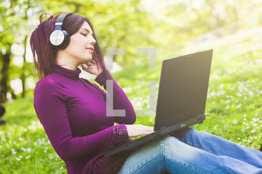 young woman listening to headphones outdoors 