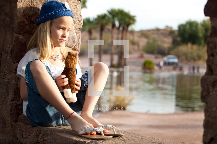 girl child sitting holding a stuffed animal horse