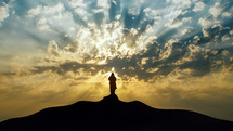 Silhouette of Jesus standing on a mount.
