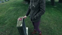 a woman putting flowers on a grave 