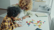 Black Mother Teaching Kid to Draw with Marker Pen on Paper at Home
