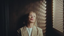 Beautiful mature woman speaking through latticed opening of confessional box while doing penance for her sins in church
