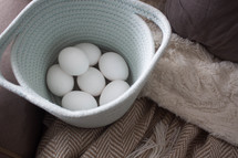 fresh eggs in a basket on a couch 