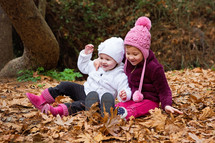 sisters playing in fall leaves 
