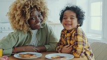 Portrait of Laughing African American Mother and Little Son during Breakfast
