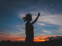 silhouette of a woman outdoors at sunset reaching for the stars 
