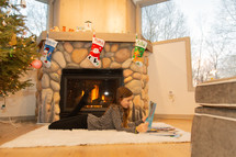 girl reading a Christmas book by a fireplace 
