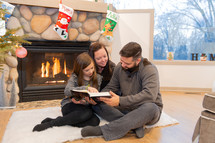 a family reading a Bible by a fireplace 