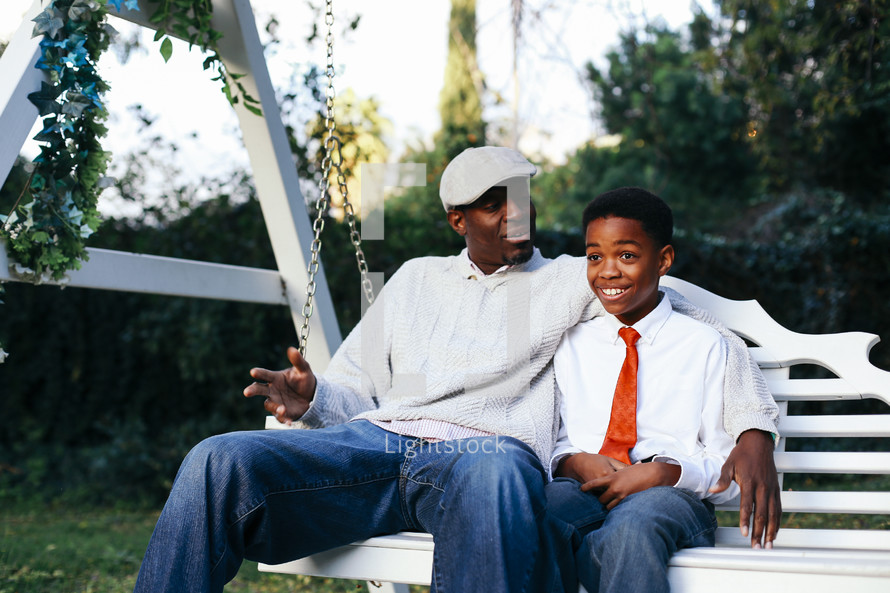 a father and son sitting on a swing 