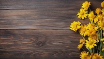 Yellow flowers on brown wooden background. Top view with copy space.