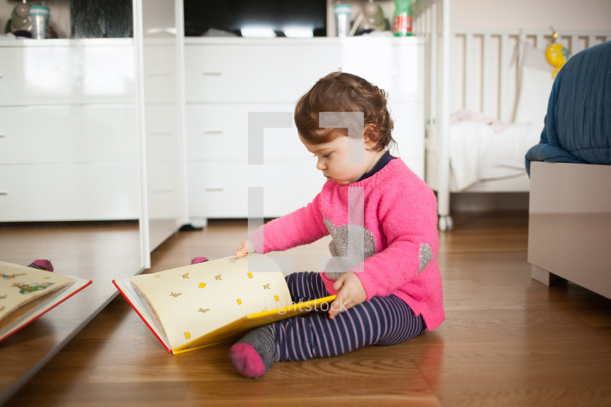 toddler girl reading a book 