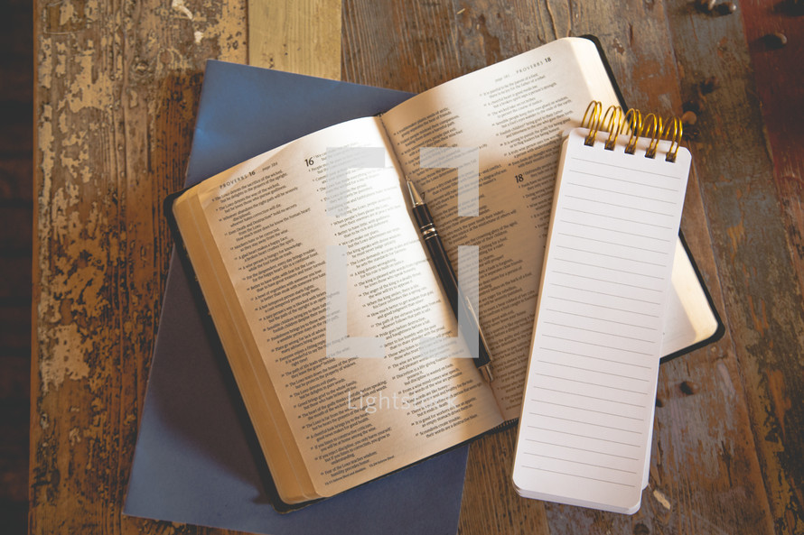 notepad, and pen on an open Bible 