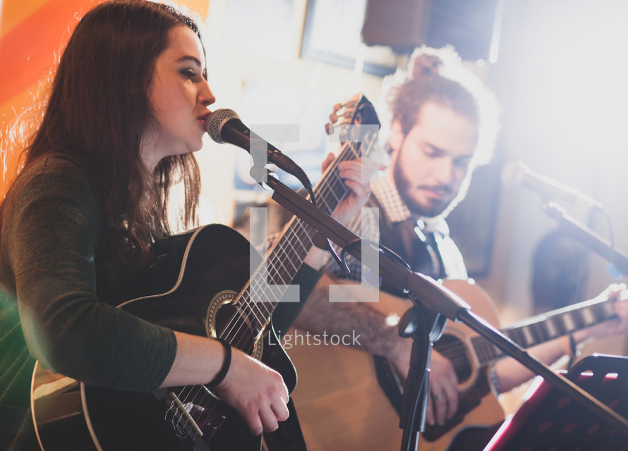 Duet of guitarists singing during a musical performance. Backlight with flare