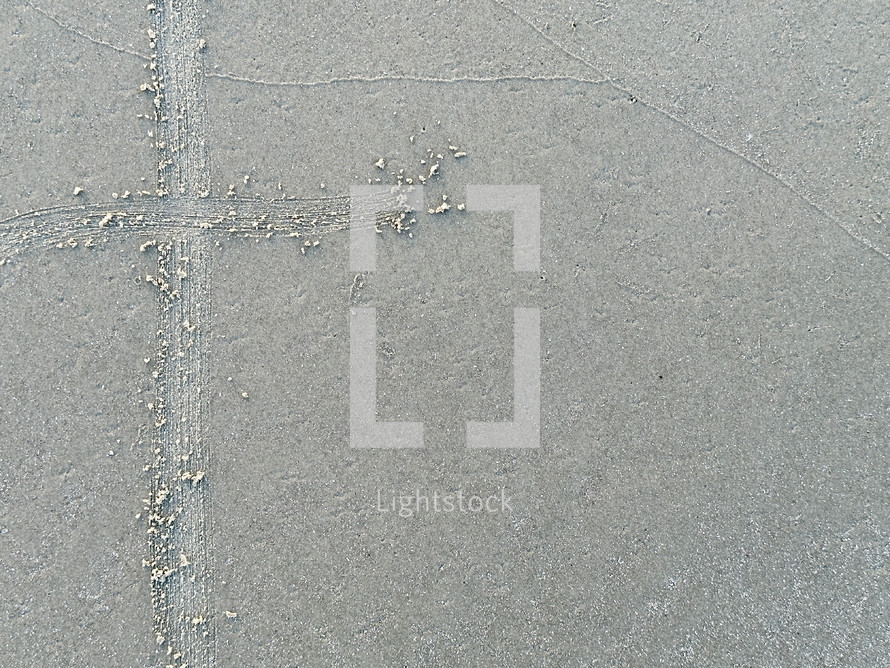 cross drawn on smooth beach sand