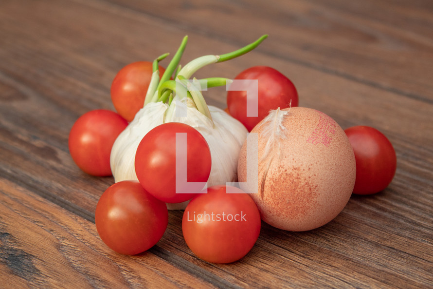 Cherry Tomatoes, Garlic and Egg on a Wooden Table