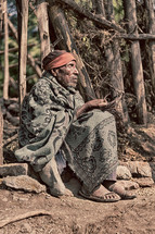 elderly man sitting on the ground wrapped in a blanket in Ethiopia 
