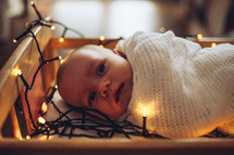 baby surrounded by Christmas lights 