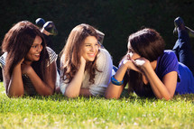 three friend lying in the grass talking 