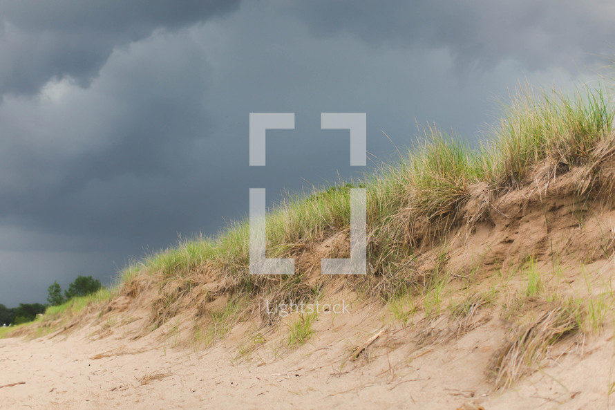 sand dune on a beach under gray skies 
