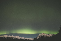 Aurora Borealis over a snow capped mountain peaks in Alaska 