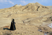 Hermit looking far into a desert - Long Shot. Religious concept of enlightenment through fasting and prayer.
