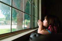 a girl praying in a window 