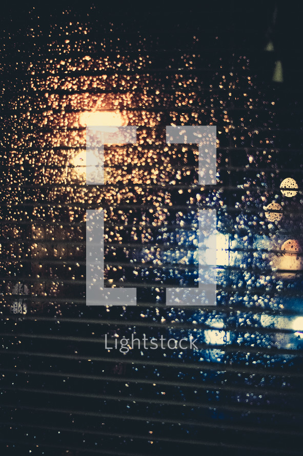 blinds and rain drops on a window at night 