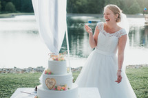 a laughing bride standing by a wedding cake 